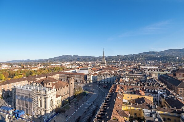 A cityscape with historic architecture, a prominent tower, and a wide street.