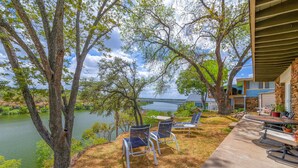Une terrasse avec mobilier d’extérieur donnant sur un lac, un bâtiment en pierre et offrant une vue sur un pont.