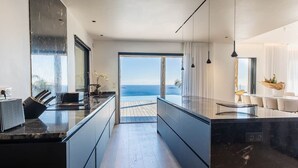 Eine moderne Küche mit Meerblick, ausgestattet mit eleganten Schränken und einer Marmarbeplatte.