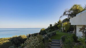 Ein Küstenanwesen mit Meerblick, einem gepflegten Garten und einem modernen Gebäude.