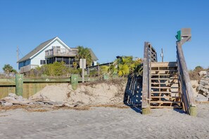 Una propiedad frente a la playa con una casa, una cerca de madera y una playa arenosa.