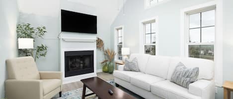 Una sala de estar con chimenea, un sofá, un sillón y una mesa de centro.