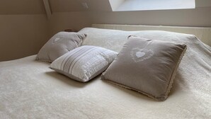 A bedroom with a skylight, a bed with a white bedspread, and three pillows with heart designs. - Domitille Deluxe Room Garden View (Lamonzie-Montastruc)