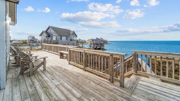 Eine Holzterrasse mit Blick auf das Meer und Häuser im Hintergrund.