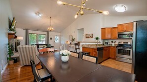 Une cuisine spacieuse dotée de meubles en bois, d’un réfrigérateur en acier inoxydable et d’un coin repas avec une table et des chaises en bois foncé.