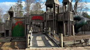 Une structure de jeu en bois, dotée d’un toboggan et d’une banderole rouge sur laquelle on peut lire : « Le grand jeu ».