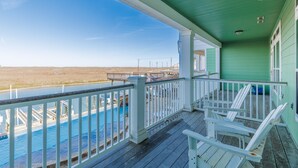 A covered porch with a view of a swimming pool and a beach. - Luxury Waterfront Townhome | Endless Coastal Views (Corpus Christi)
