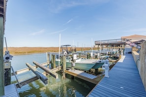 A dock with boats, a wooden walkway, and a building with a balcony.