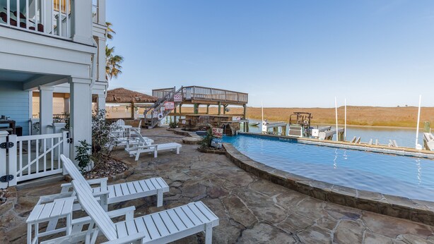 A pool area with lounge chairs, a deck, and a view of the water. - Luxury Waterfront Townhome | Endless Coastal Views (Corpus Christi)