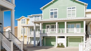 A two-story house with a green exterior, white railings, and a front porch. - Luxury Waterfront Townhome | Endless Coastal Views (Corpus Christi)