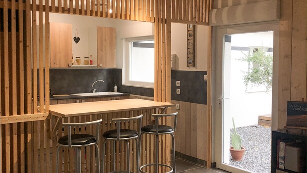 A modern kitchen with a wooden bar area, a sink, and stools. - La Maisonnette de Fred et Marie (Andernos-les-Bains)