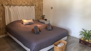 A bedroom with a bed, a nightstand, a potted plant, and a wall-mounted picture. - La Maisonnette de Fred et Marie (Andernos-les-Bains)