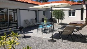 A patio area with a table and chairs, a grill, and a covered seating area. - La Maisonnette de Fred et Marie (Andernos-les-Bains)