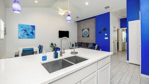 A modern kitchen with a large island, white cabinetry, and blue accents. - Experience a ‘blu-tiful’ retreat: Pet-Friendly, Private Patio, Pool & More (Corpus Christi)