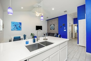 Een moderne keuken met een groot eiland, witte kastjes en blauwe accenten.