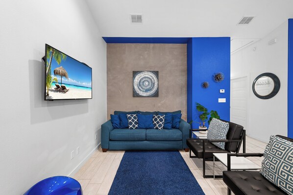 A modern living room with a blue sofa, a coffee table, and a blue rug. - Experience a ‘blu-tiful’ retreat: Pet-Friendly, Private Patio, Pool & More (Corpus Christi)