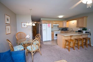 Enjoy meals in the kitchen and dining area, featuring a stove, microwave, and round table with wicker chairs.