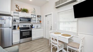 Une cuisine moderne avec des meubles blancs, un four encastré, un four à micro-ondes et un coin repas comprenant une table et des chaises.