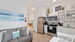 Une cuisine moderne avec des meubles blancs, des appareils en acier inoxydable et un coin repas comprenant une table et des chaises blanches.
