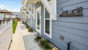 Une rangée de maisons avec une enseigne en bois sur le côté, sur laquelle on peut lire « PLAGE ».