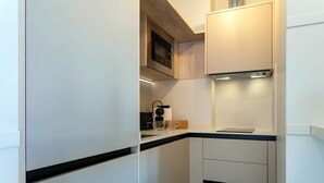 A modern kitchen with white cabinets, a black countertop, and a built-in microwave. - Genteel Home San Francisco III (Seville)
