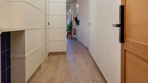 A hallway with wooden flooring, a wooden door on the right, and a ceiling with a skylight. - Genteel Home San Francisco III (Seville)