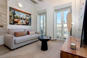 A living room with a sofa, a round black coffee table, and a large painting of giraffes. - Amazing loft in Seville center. San Francisco III (Seville)
