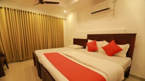 A hotel room with a large bed, a wooden headboard, a red and white bedspread, and a ceiling fan. - Diamond Residency (Ambalapuzha)