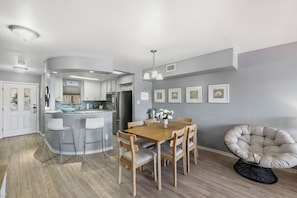 Une cuisine moderne avec un coin repas, des chaises en bois, une table ronde et un fauteuil original en forme d’œuf.