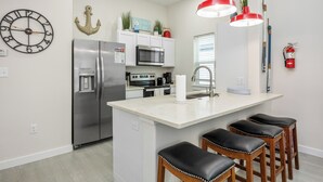 A modern kitchen with a central island, stainless steel appliances, and a red pendant light.
