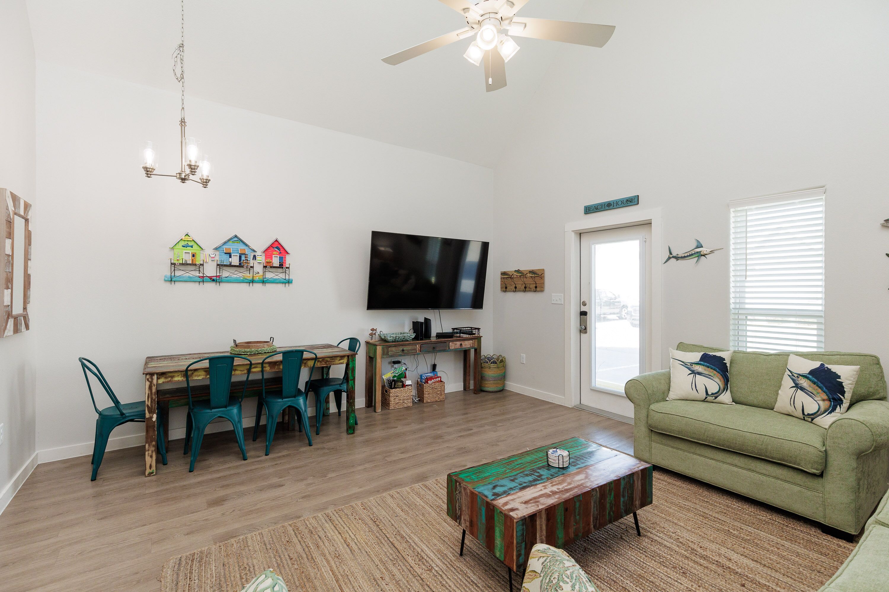 Relax in your bright coastal living room where green sofas invite lazy afternoons and the dining table awaits family meals.