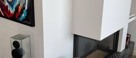 A modern living room with a fireplace, a colorful abstract painting, and a glass sculpture.