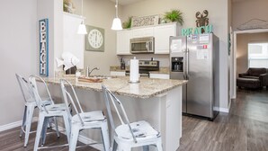 Una cucina moderna con isola centrale, elettrodomestici in acciaio inossidabile e un’area relax con sedute.