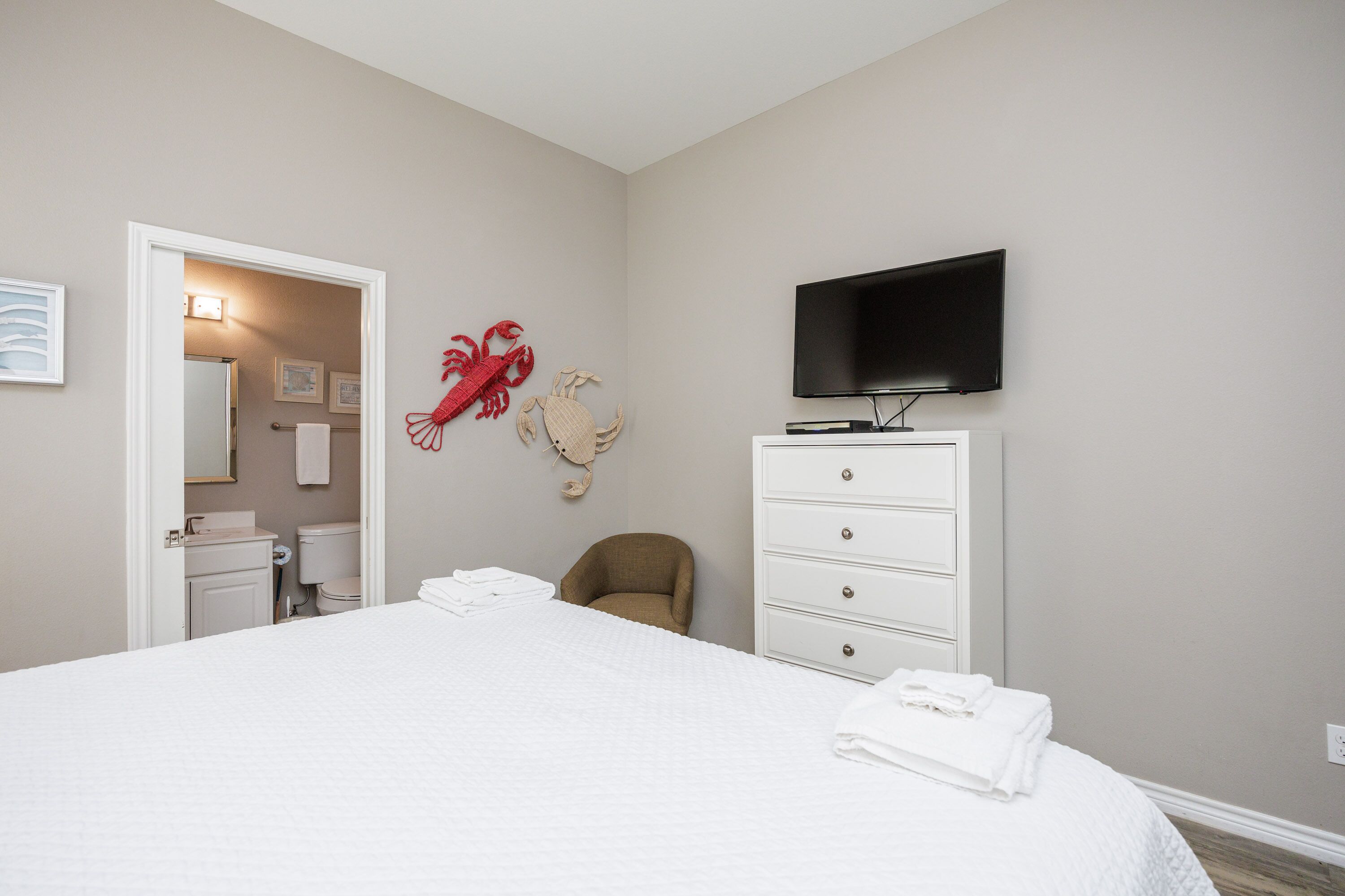 Sink into crisp white linens in your serene bedroom, complete with coastal charm and modern amenities for ultimate comfort.