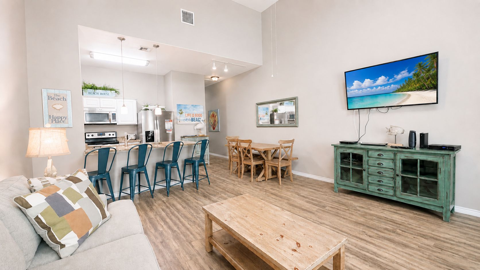 Una sala de estar moderna con sofá, mesa de centro y televisor mostrando una escena de playa.