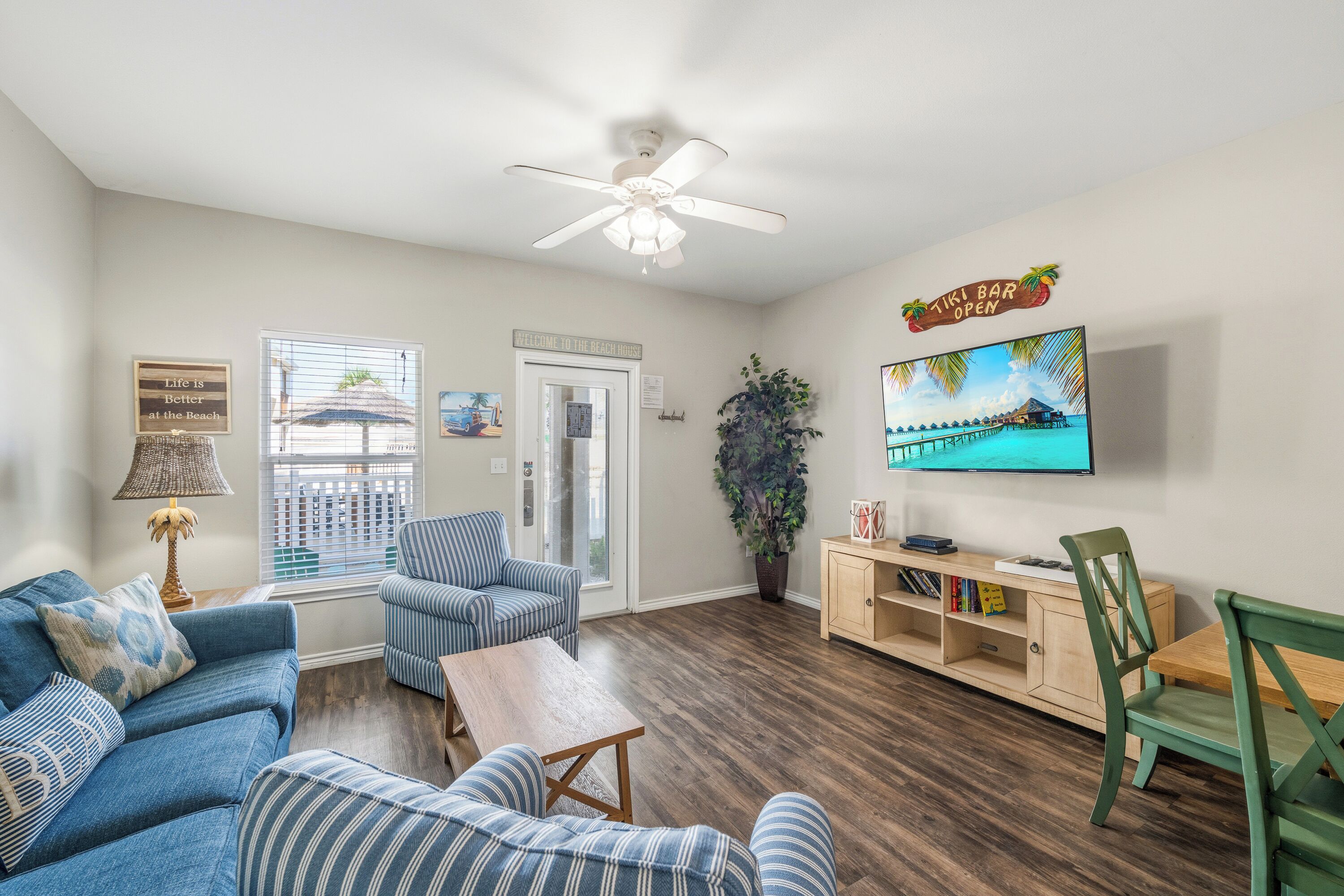 A living room with a sofa, armchair, coffee table, and a TV mounted on the wall.