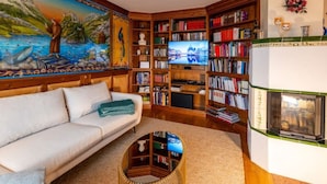 Un salon chaleureux avec un canapé blanc, une cheminée et une bibliothèque remplie de livres.