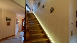 Un escalier en bois avec un palier recouvert de moquette et un mur orné de tableaux encadrés.