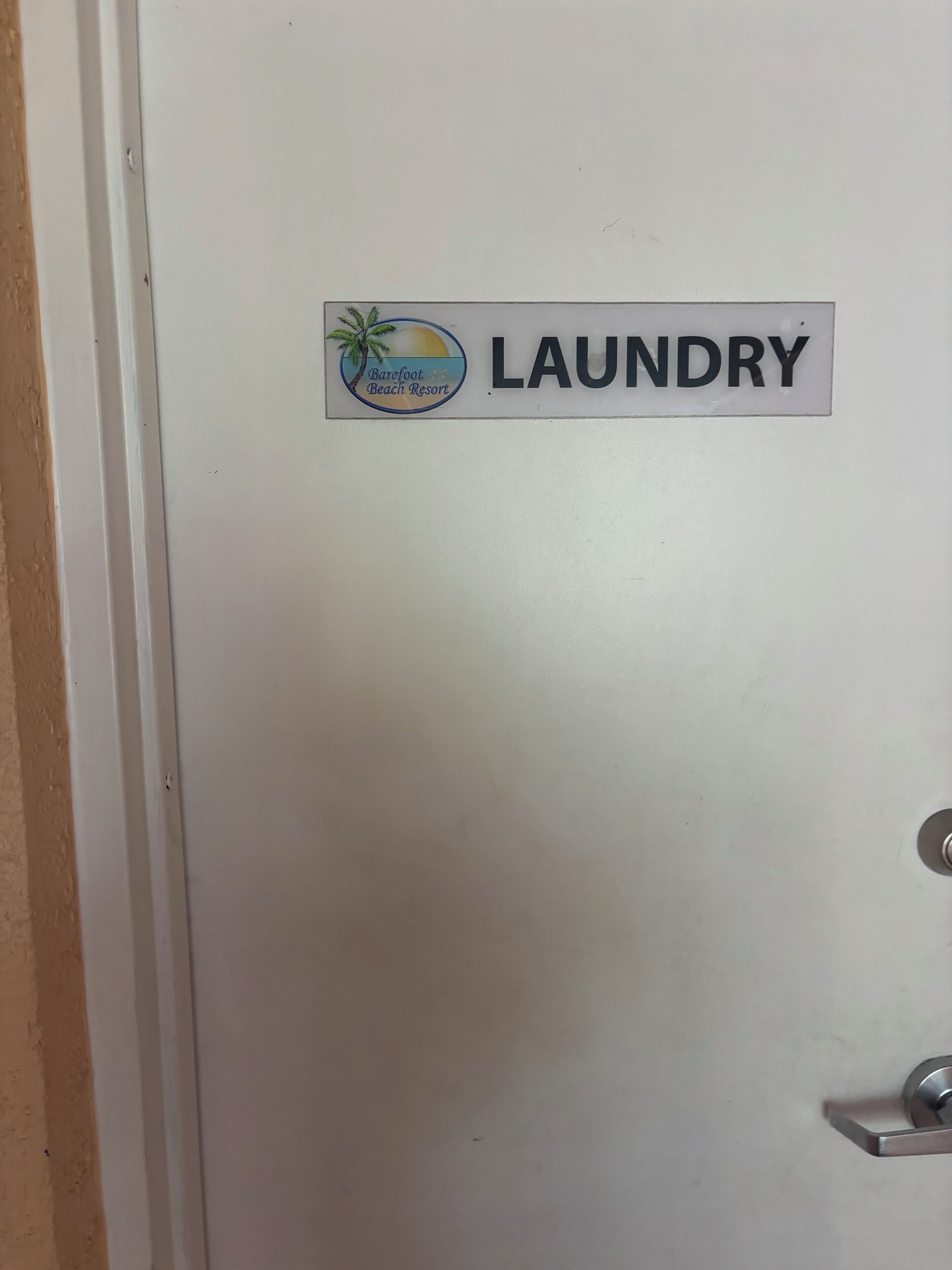 Una puerta con un letrero que dice "LAUNDRY" y el logotipo del Barefoot Beach Resort.