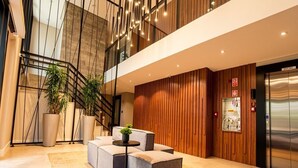 A modern lobby with a staircase, seating area, and an elevator.