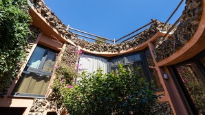 A building with a curved stone facade, large windows, and a balcony with a wooden railing. - Villa in Sardinia overlooking the sea (Porto Sa Ruxi)