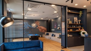 Ein moderner Lounge-Bereich mit blauem Sofa, einer Poolbillardkugel und einer Bar mit Regalen und Dekoration.