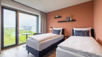 Una habitación de hotel moderna con dos camas, un balcón y vistas a la ciudad, además de una pequeña mesa.