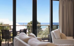 Un balcon avec vue sur l’océan, un canapé blanc et un fauteuil.