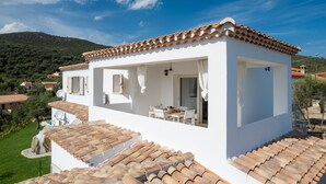 A white villa with a tiled roof, a balcony, and a dining area. - Bellevue 36B by Klodge - flat with pool and views (Budoni)