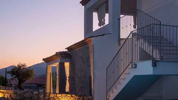 A poolside view of a house with a stone facade, a balcony, and a staircase leading to an upper level. - Bellevue 36B by Klodge - flat with pool and views (Budoni)