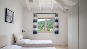 A bedroom with two beds, a window with curtains, a framed picture on the wall, and a view of a green landscape. - Bellevue 36B by Klodge - flat with pool and views (Budoni)