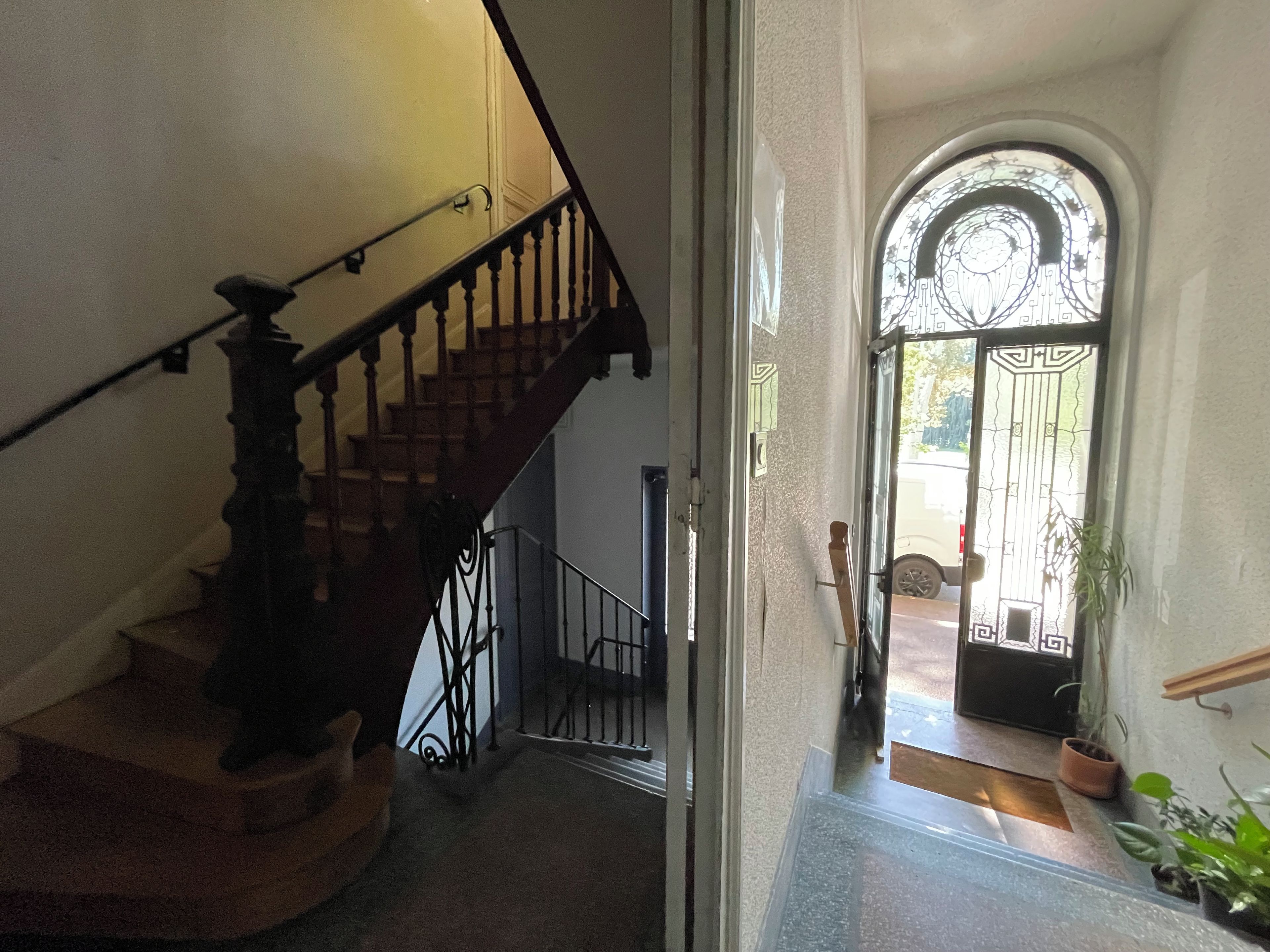 Escada com corrimão e porta que dá para área externa com portão.