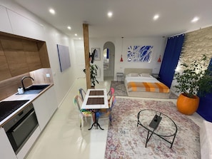 A modern apartment with a kitchen, dining area, and a bedroom.