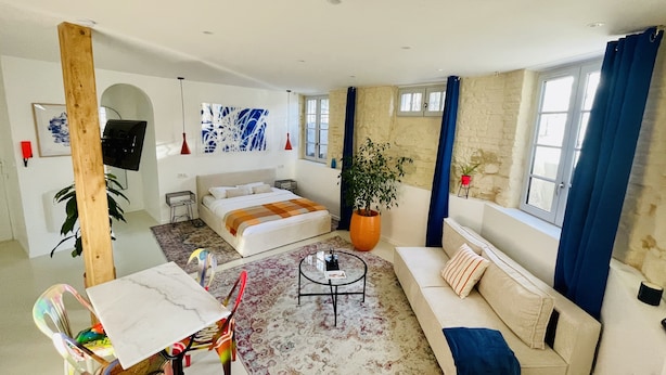 A modern living room with a sofa, a coffee table, a TV, and a large window with curtains. - Studio 11 bis – Facing Vichy Parks (Vichy)